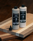 Two bottles of BOSSDOG glue products on a wooden cutting board.