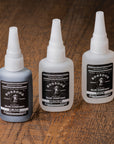 Three bottles of BOSSDOG Glue Company products on a wooden surface