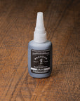Bottle of BOSSDOG Black Glue on a wooden surface