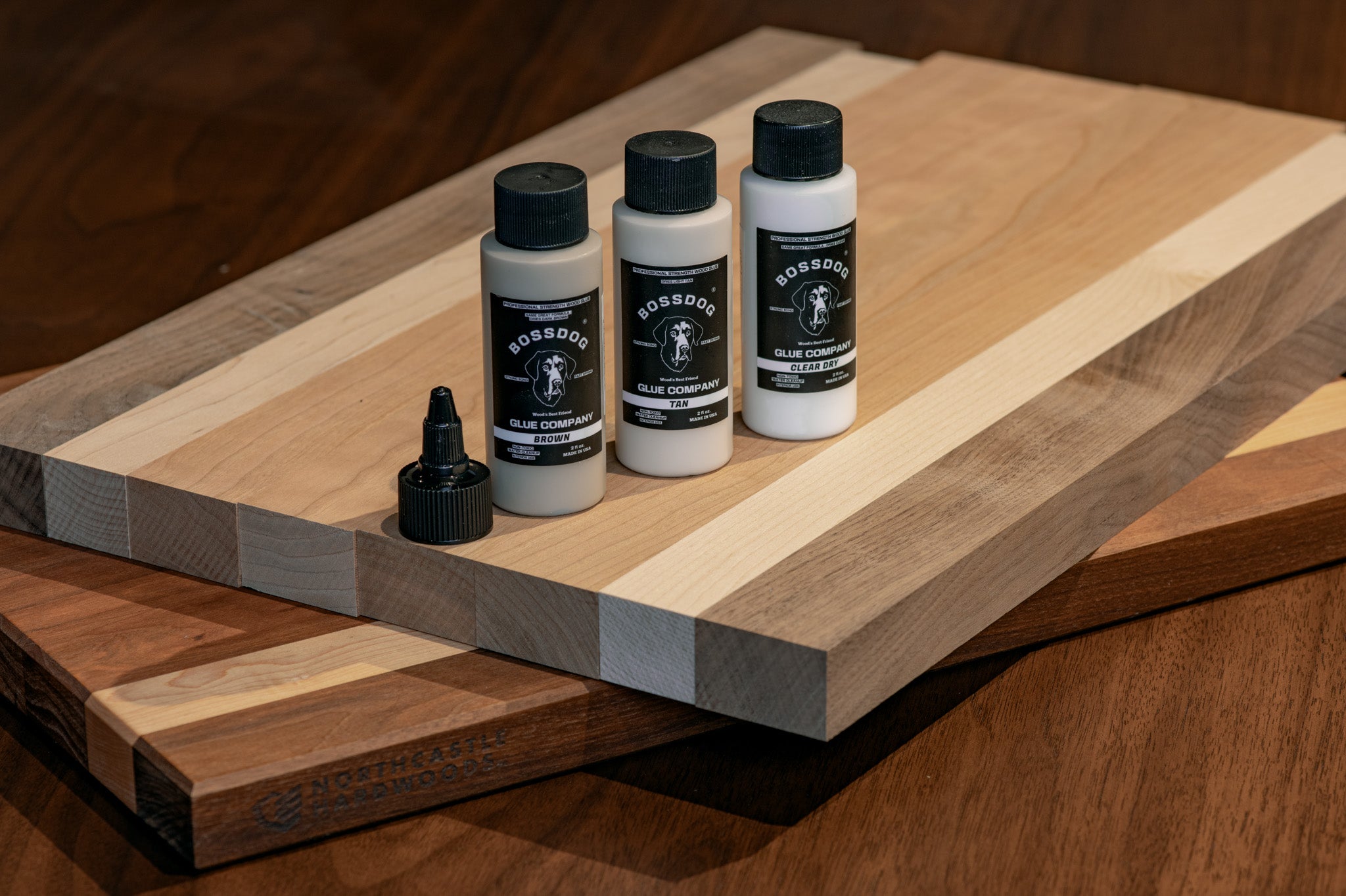 Three bottles of BOSSDOG products on a wooden surface
