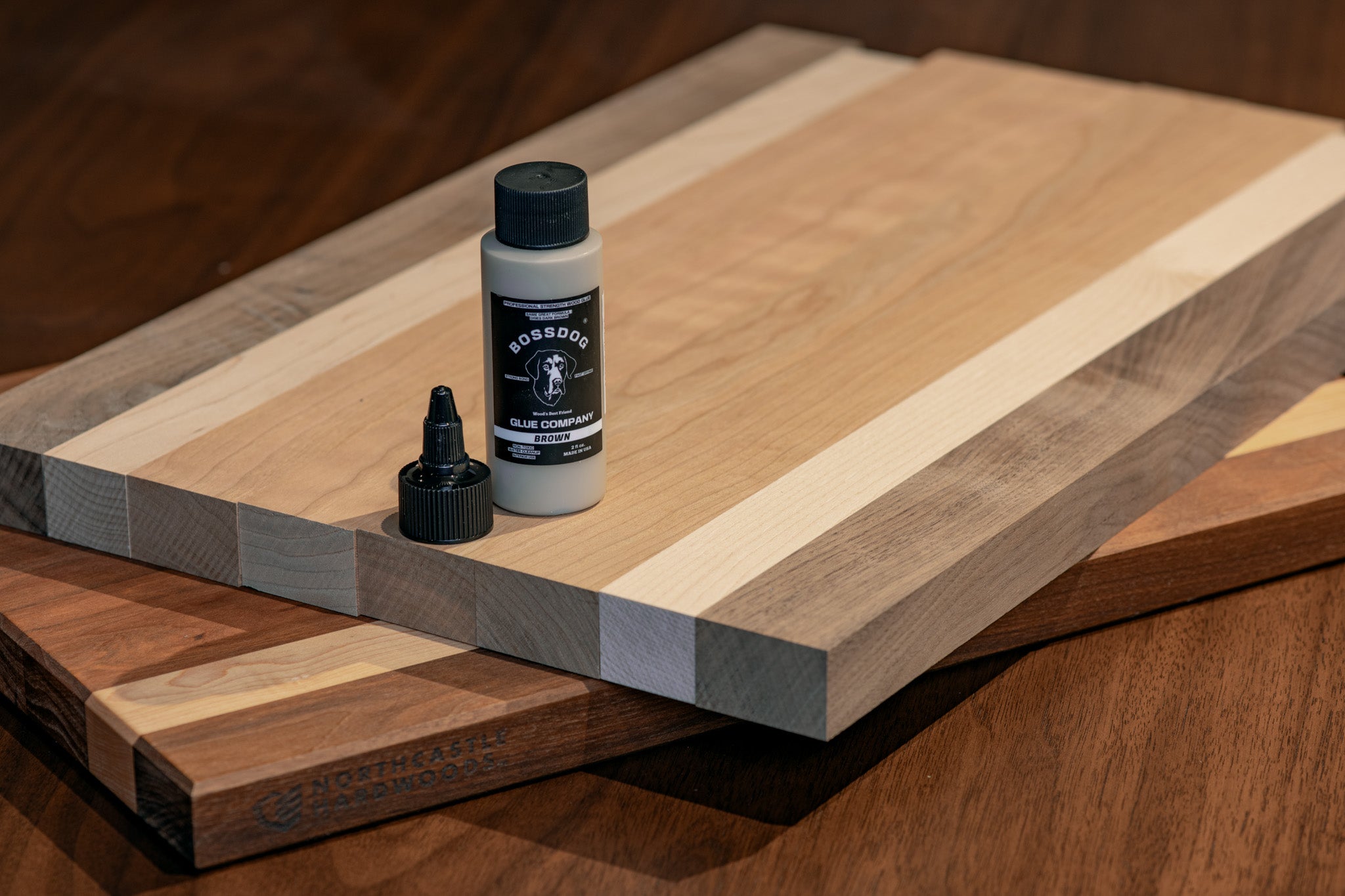 A cutting board with a bottle of BOSSDOG wood glue on top 