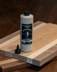 Bottle of a BOSSDOG glue product on a wooden cutting board with a dark background