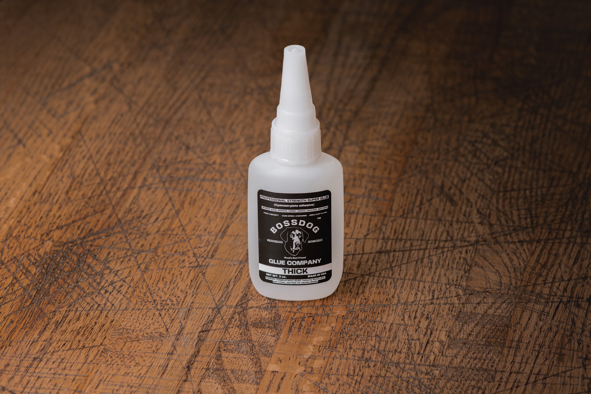 Bottle of BOSSDOG Glue on a wooden surface