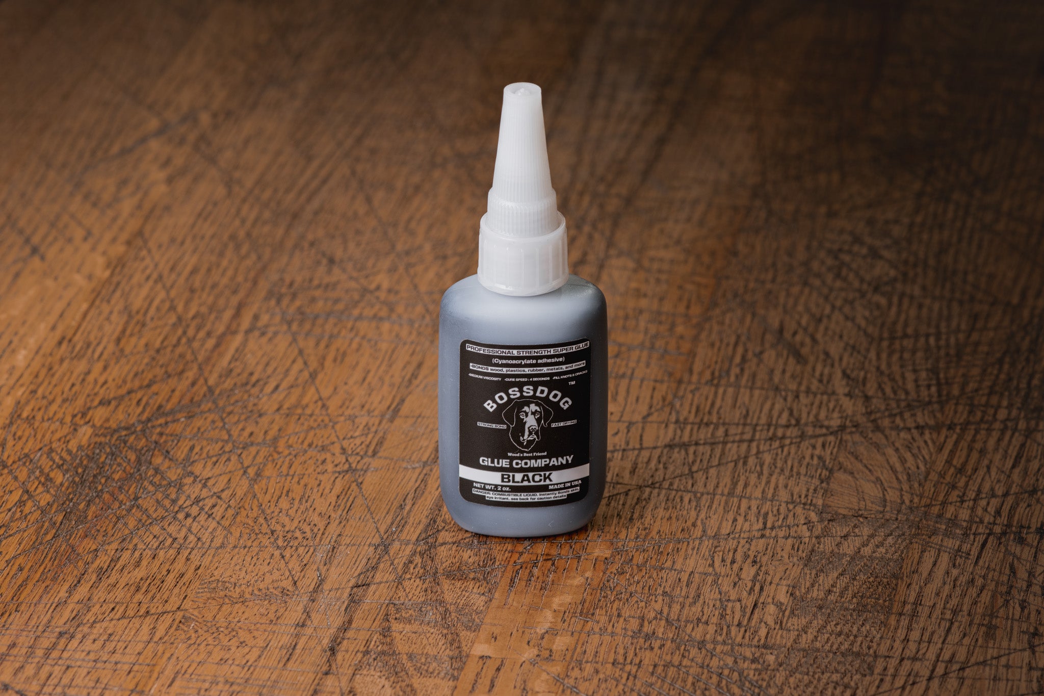 Bottle of BOSSDOG Black Glue on a wooden surface