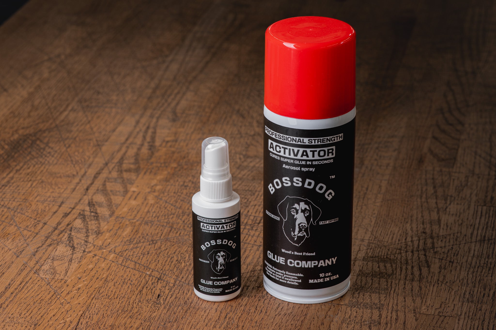 Two bottles of BossDog Glue Company activator on a wooden surface